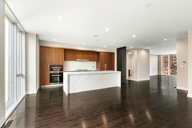 kitchen with brown cabinets, ventilation hood, light countertops, visible vents, and modern cabinets