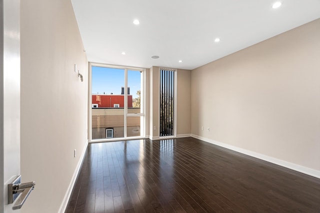 spare room with baseboards, recessed lighting, dark wood finished floors, and expansive windows