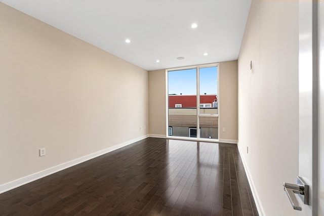 spare room with dark wood-type flooring, recessed lighting, and baseboards