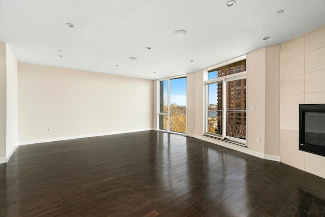 unfurnished living room with a fireplace, baseboards, wood-type flooring, and recessed lighting