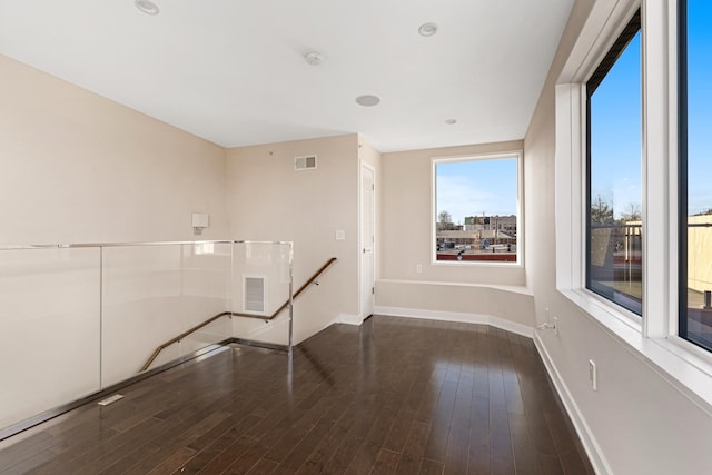 spare room with baseboards, wood finished floors, and visible vents