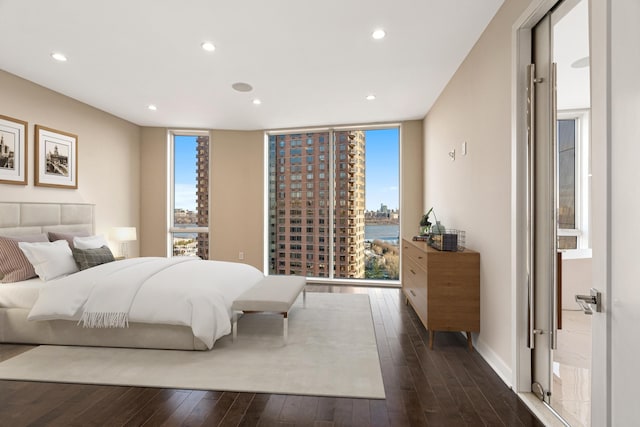 bedroom with a wall of windows, recessed lighting, multiple windows, and dark wood-style flooring