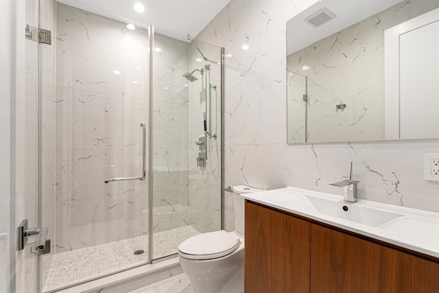 bathroom featuring vanity, toilet, a marble finish shower, tile walls, and visible vents