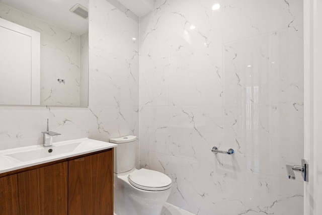 bathroom with vanity, visible vents, toilet, and tile walls