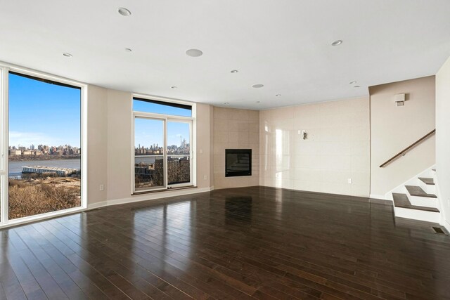 5 Washington Pl Unit 5-05, Cliffside Park, NJ 07010 - unfurnished living room featuring a tiled fireplace, a water view, hardwood / wood-style floors, and stairway