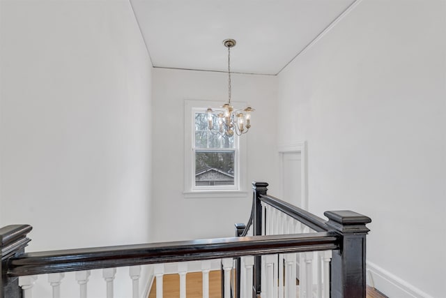 stairway featuring an inviting chandelier, baseboards, and wood finished floors