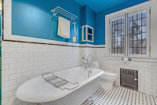 full bathroom featuring toilet, tile walls, radiator heating unit, a wainscoted wall, and a soaking tub