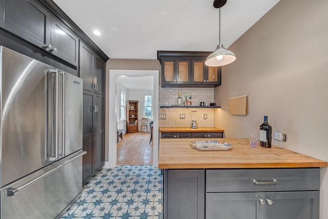 kitchen featuring backsplash, wooden counters, decorative light fixtures, high quality fridge, and light floors