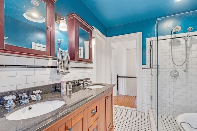 full bath with a sink, tile patterned floors, a shower stall, and double vanity