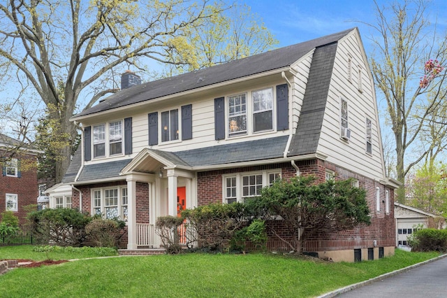 view of front of home with brick siding, a chimney, a front yard, and a gambrel roof