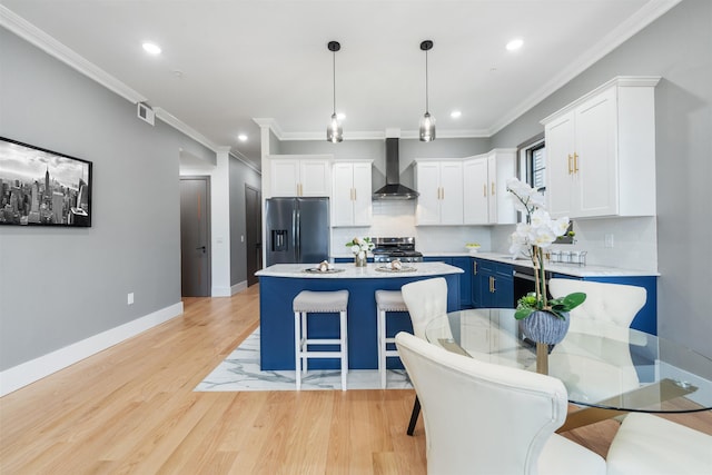 kitchen featuring blue cabinets, white cabinetry, light countertops, appliances with stainless steel finishes, and wall chimney range hood