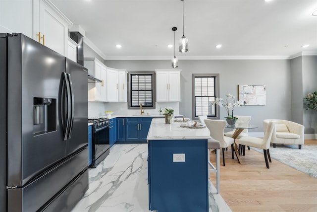 kitchen with stainless steel fridge, decorative light fixtures, black range with gas stovetop, blue cabinetry, and white cabinetry