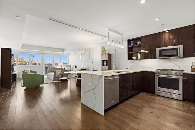 kitchen with dark wood-type flooring, modern cabinets, a sink, appliances with stainless steel finishes, and dark brown cabinets