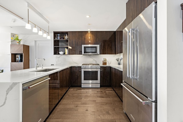 kitchen featuring high quality appliances, modern cabinets, a sink, wood finished floors, and dark brown cabinetry