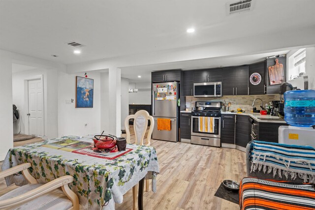 70 County Ave, Secaucus, NJ 07094 - kitchen with stainless steel appliances, dark cabinets, light countertops, light wood-style flooring, and decorative backsplash