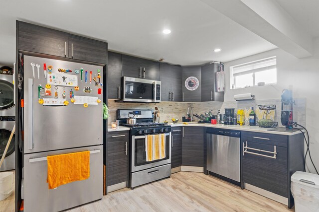 70 County Ave, Secaucus, NJ 07094 - kitchen featuring appliances with stainless steel finishes, estacked washer and dryer, light countertops, light wood finished floors, and tasteful backsplash