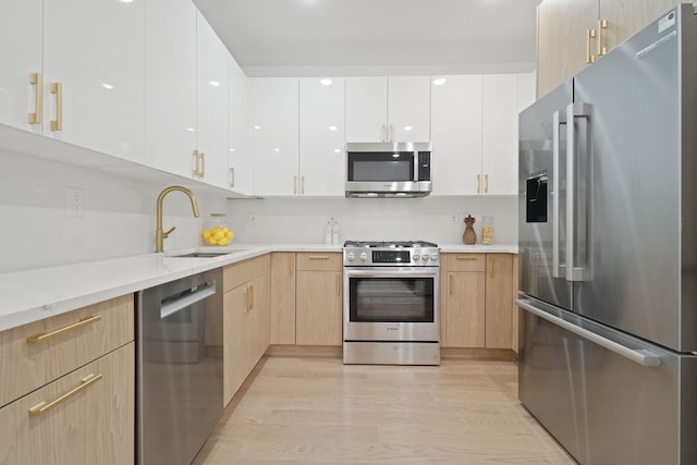 kitchen with light hardwood / wood-style floors, sink, stainless steel appliances, and light brown cabinetry