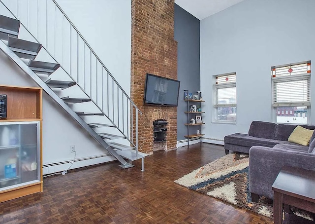 living room featuring parquet flooring, a towering ceiling, a baseboard radiator, and a wood stove