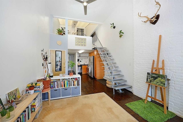 stairway featuring hardwood / wood-style floors, a towering ceiling, and brick wall