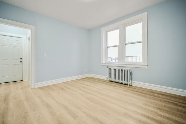 spare room featuring radiator and light hardwood / wood-style floors