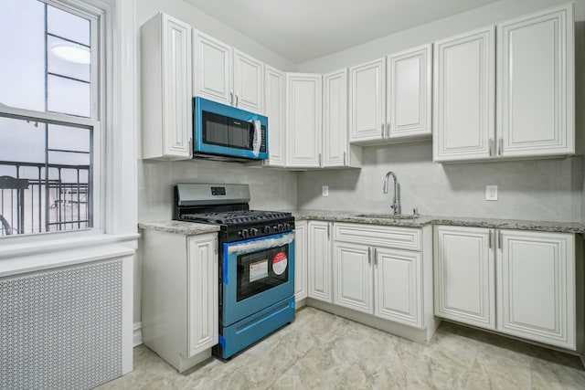 kitchen with sink, light stone countertops, gas stove, and white cabinets