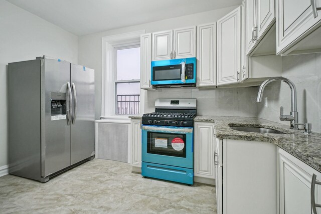 kitchen featuring gas range, sink, backsplash, and light stone counters