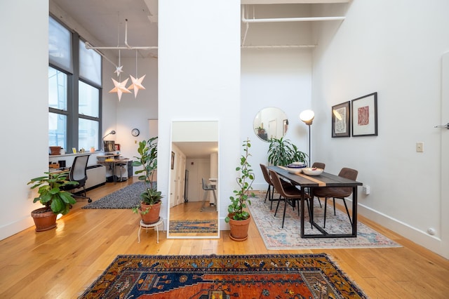 dining space with hardwood / wood-style floors, a high ceiling, and baseboards