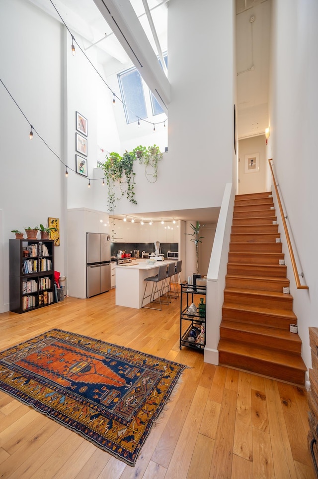 stairs with a skylight, a towering ceiling, and hardwood / wood-style flooring