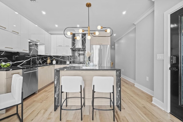 kitchen with a kitchen island, white cabinets, appliances with stainless steel finishes, modern cabinets, and decorative light fixtures