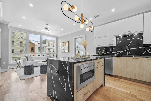 kitchen featuring a kitchen island, white cabinetry, open floor plan, hanging light fixtures, and appliances with stainless steel finishes