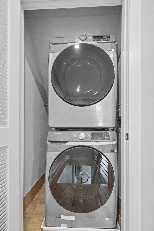 laundry room with baseboards, laundry area, stacked washer / dryer, and tile patterned floors