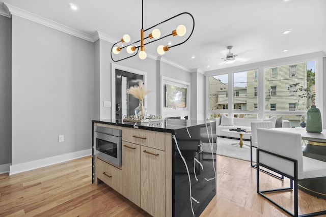 kitchen featuring open floor plan, light brown cabinetry, stainless steel microwave, dark countertops, and modern cabinets