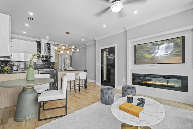 dining space featuring visible vents, baseboards, a glass covered fireplace, ornamental molding, and light wood-type flooring