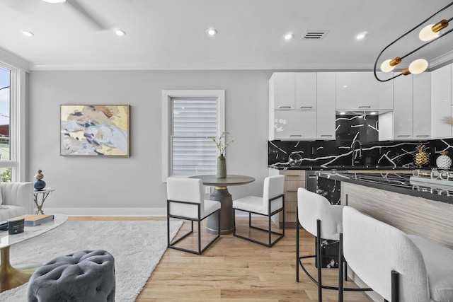 kitchen featuring visible vents, white cabinets, light wood-type flooring, decorative backsplash, and modern cabinets