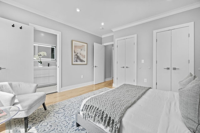 bedroom featuring crown molding, two closets, connected bathroom, light wood-type flooring, and baseboards