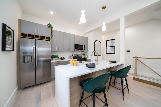 79 Vroom St Unit 1, Jersey City, NJ 07306 - kitchen with appliances with stainless steel finishes, gray cabinetry, light wood-style flooring, a breakfast bar, and light countertops