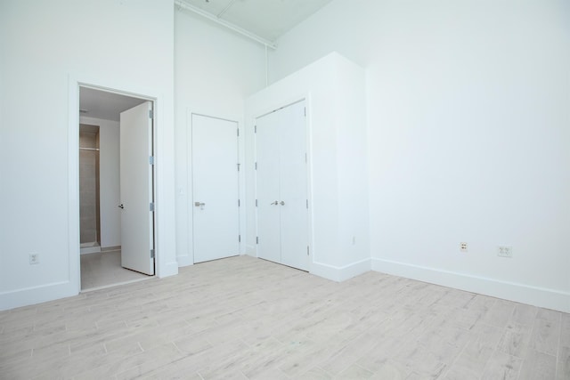 unfurnished bedroom featuring connected bathroom and light wood-type flooring