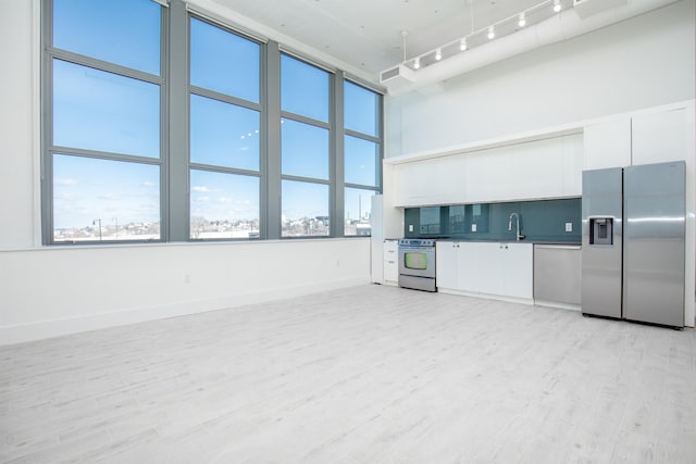 kitchen with light hardwood / wood-style flooring, stainless steel appliances, and white cabinets