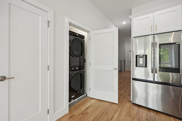 laundry room with stacked washer and dryer and light hardwood / wood-style flooring