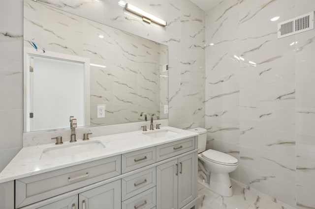 bathroom featuring vanity, toilet, and tile walls