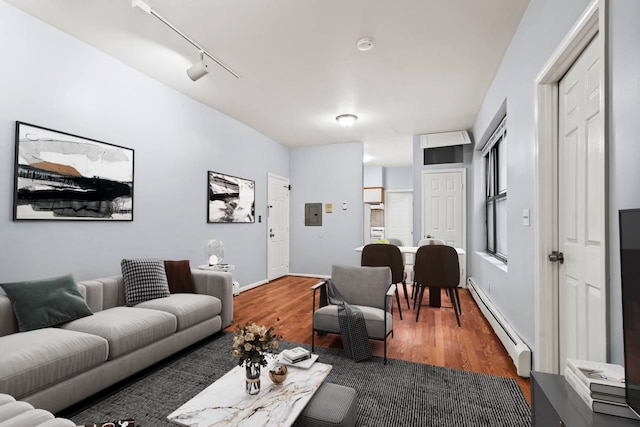 living room with rail lighting, dark hardwood / wood-style floors, and a baseboard heating unit