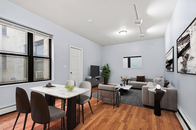 interior space featuring light hardwood / wood-style flooring, rail lighting, and a baseboard heating unit