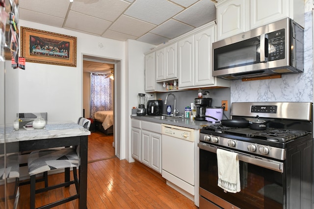 kitchen featuring sink, white cabinetry, appliances with stainless steel finishes, light hardwood / wood-style floors, and backsplash