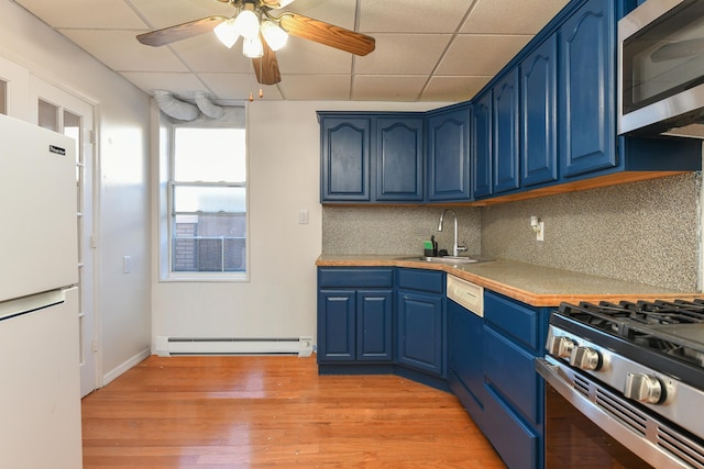 kitchen featuring sink, blue cabinetry, baseboard heating, appliances with stainless steel finishes, and backsplash