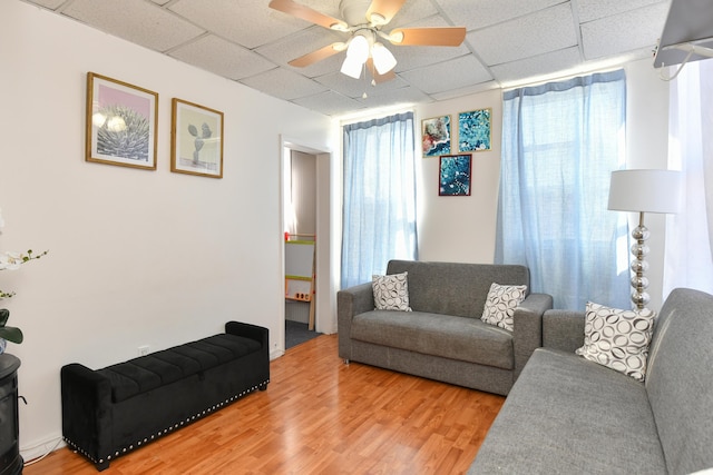 living room with hardwood / wood-style floors, a drop ceiling, and ceiling fan