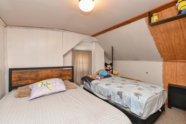 bedroom with lofted ceiling, carpet flooring, and wood walls