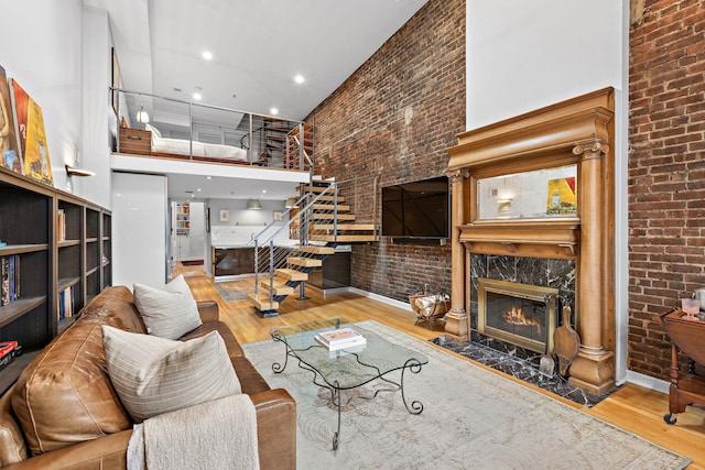 1110 Hudson St Unit 5B, Hoboken, NJ 07030 - living room featuring a high ceiling, brick wall, stairs, wood finished floors, and a high end fireplace
