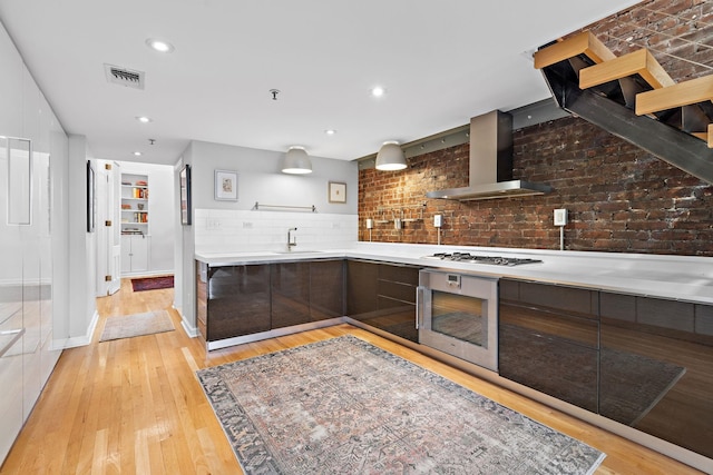 1110 Hudson St Unit 5B, Hoboken, NJ 07030 - kitchen featuring modern cabinets, wall chimney range hood, appliances with stainless steel finishes, light countertops, and light wood-style flooring