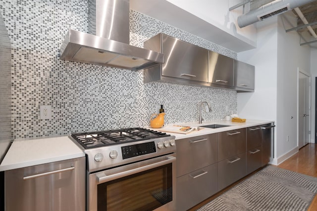 140 Bay St Unit 6G, Jersey City, NJ 07302 - kitchen with wall chimney range hood, stainless steel gas range oven, light countertops, tasteful backsplash, and wood finished floors