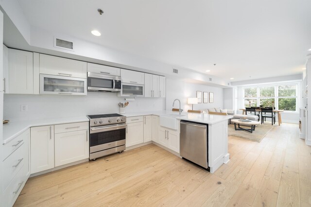 833 Willow Ave Unit 2, Hoboken, NJ 07030 - kitchen featuring appliances with stainless steel finishes, a peninsula, open floor plan, white cabinets, and light wood finished floors